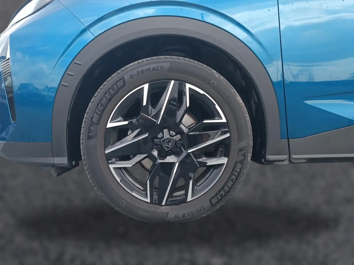 Gros plan sur la roue avant droite d’un Peugeot 3008 bleu avec jante alliage noire et argentée.