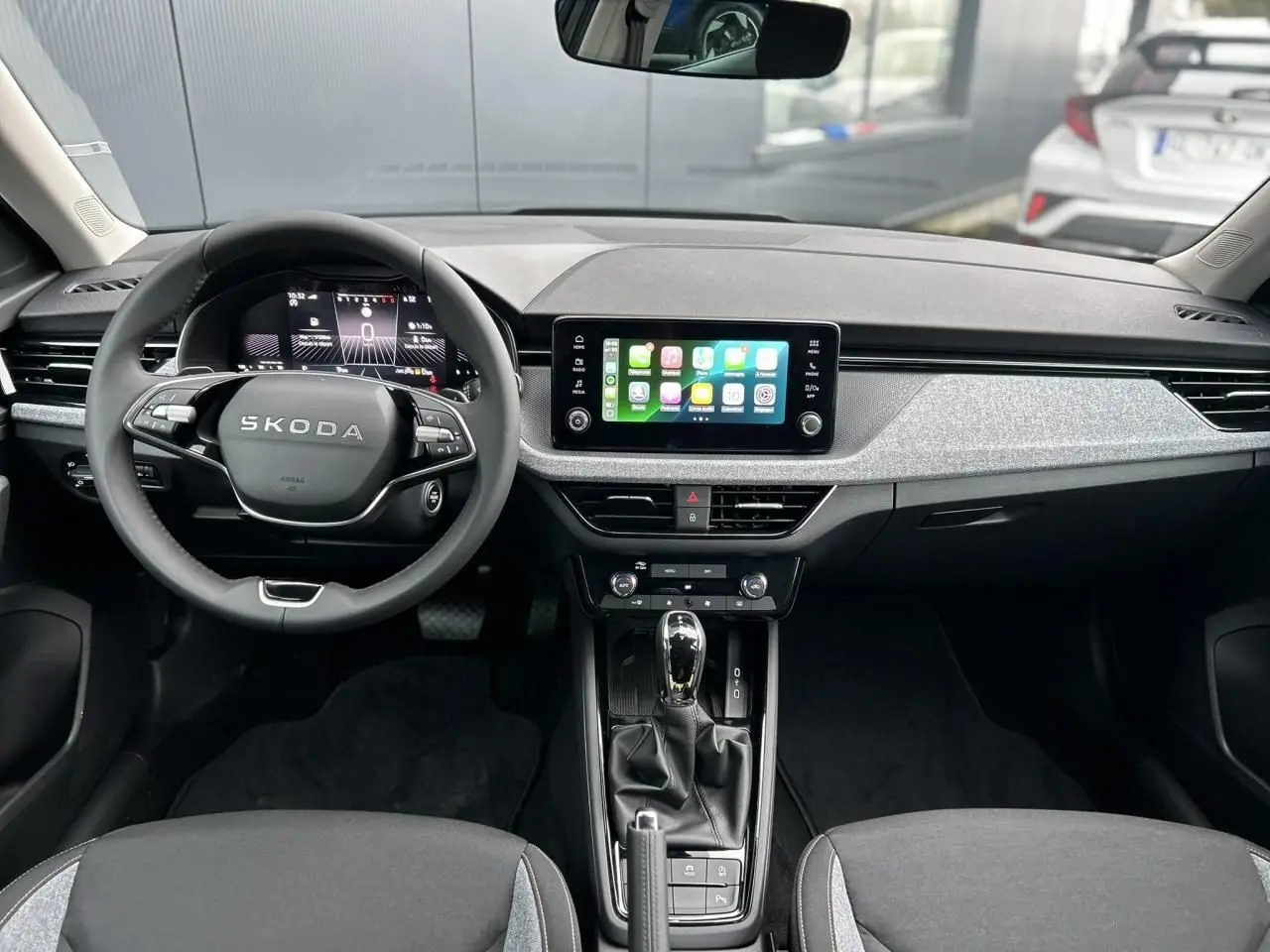 Vue intérieure avant du Skoda Kamiq noir Magic 2025, tableau de bord avec écran tactile Apple CarPlay et volant multifonctions.