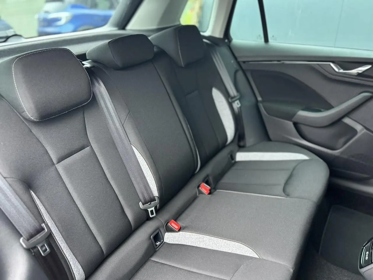 Vue intérieure du siège arrière droit d'une Skoda Kamiq noir Magic, avec ceintures et garnitures grises contrastantes.