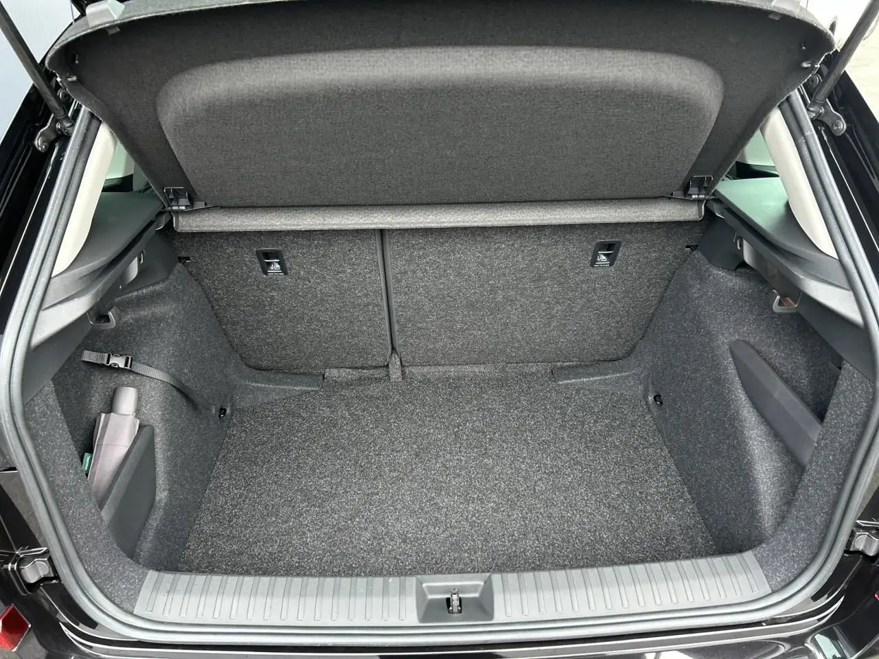 Coffre ouvert vu de l'arrière d'un Skoda Kamiq noir Magic, montrant un espace de chargement propre et bien fini.