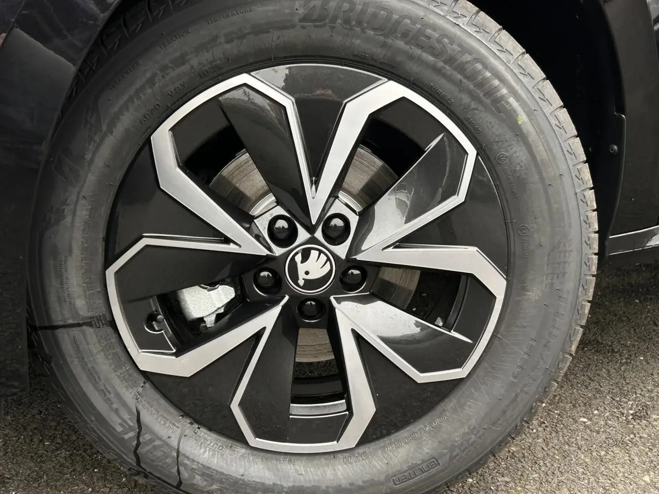 Gros plan sur la jante alliage 16 pouces noire et argentée du Skoda Kamiq noir Magic, avec logo central visible.