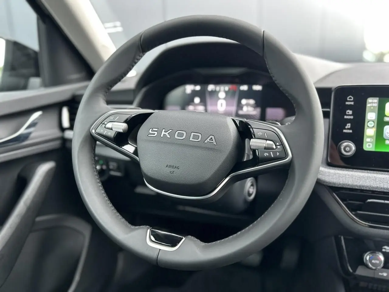 Vue rapprochée du volant cuir noir multifonctions SKODA KAMIQ 2025 avec tableau de bord digital et écran tactile Apple CarPlay.