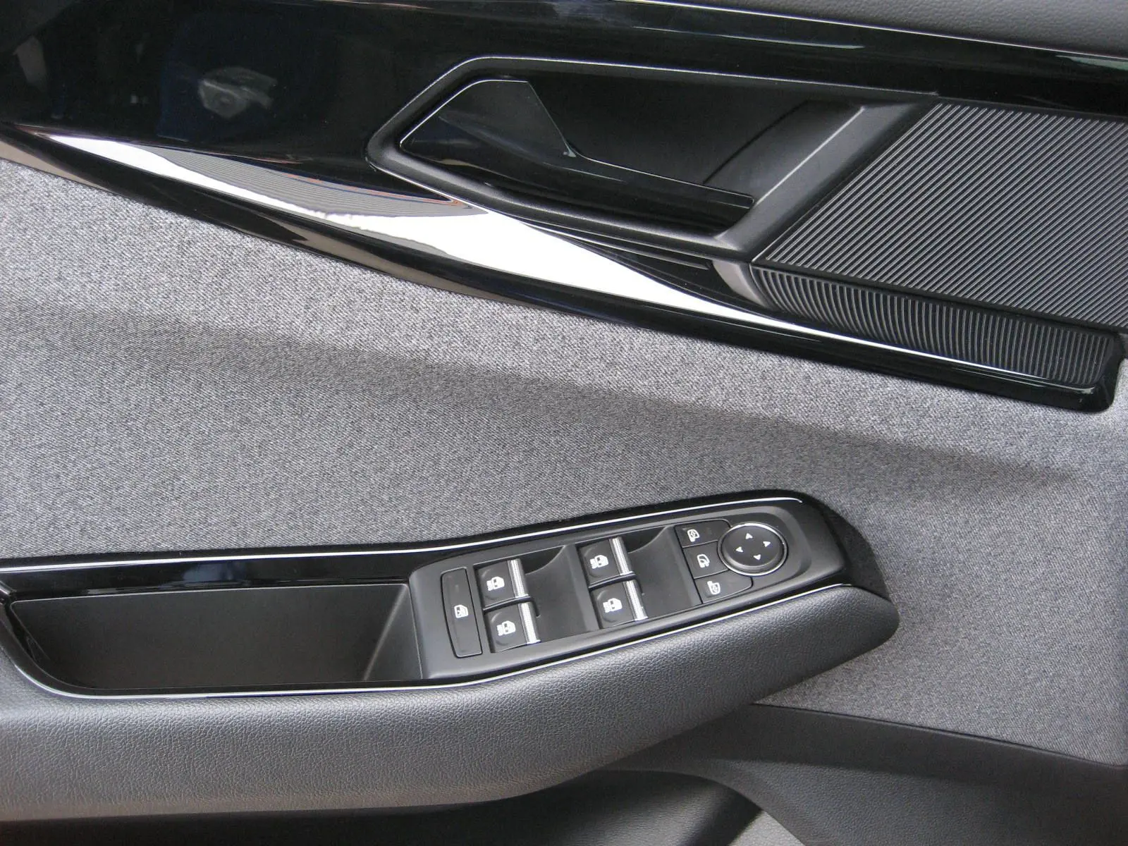 Détail de la porte côté gauche du Renault Austral 2025 bleu iron, montrant les commandes des vitres et la poignée intérieure.