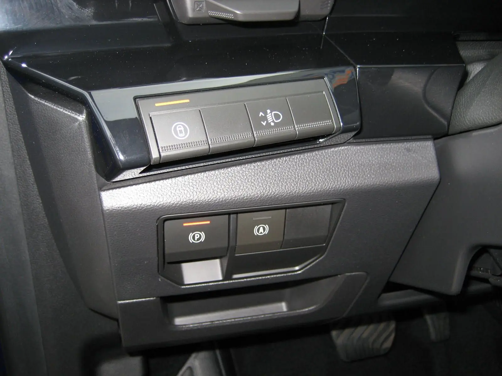 Gros plan sur les commandes de réglage des feux et frein de stationnement du Renault Austral 2025, intérieur noir.
