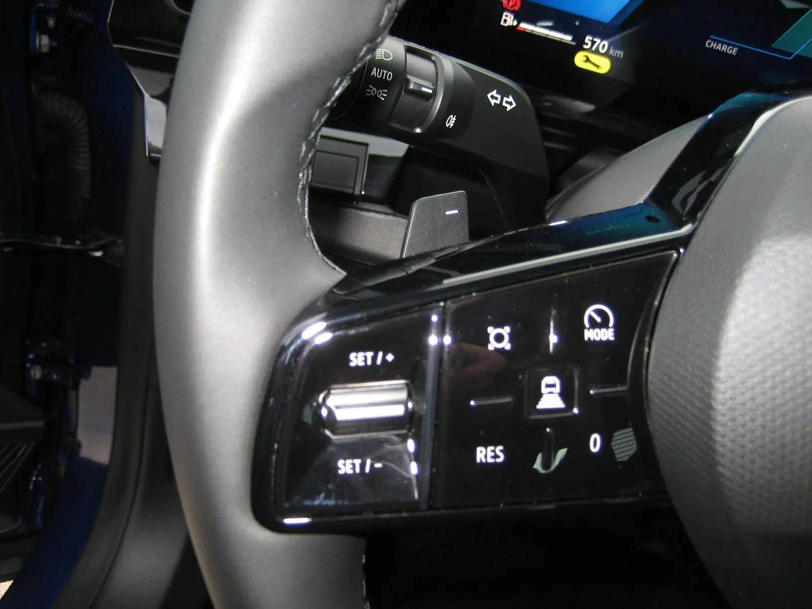 Gros plan sur les commandes au volant du Renault Austral bleu Iron, avec affichage digital et boutons de régulateur de vitesse.