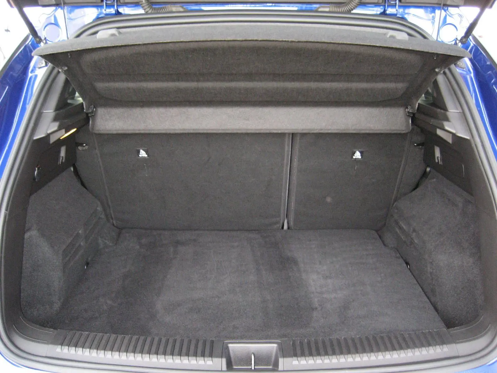 Coffre ouvert vu de l'arrière d'un Renault Austral bleu Iron, montrant l'espace de chargement vide et la tablette cache-bagages.