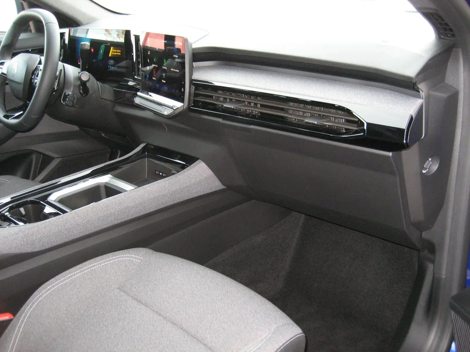 Vue intérieure côté passager du tableau de bord du Renault Austral 2025 avec écran tactile et finition moderne gris et noire.