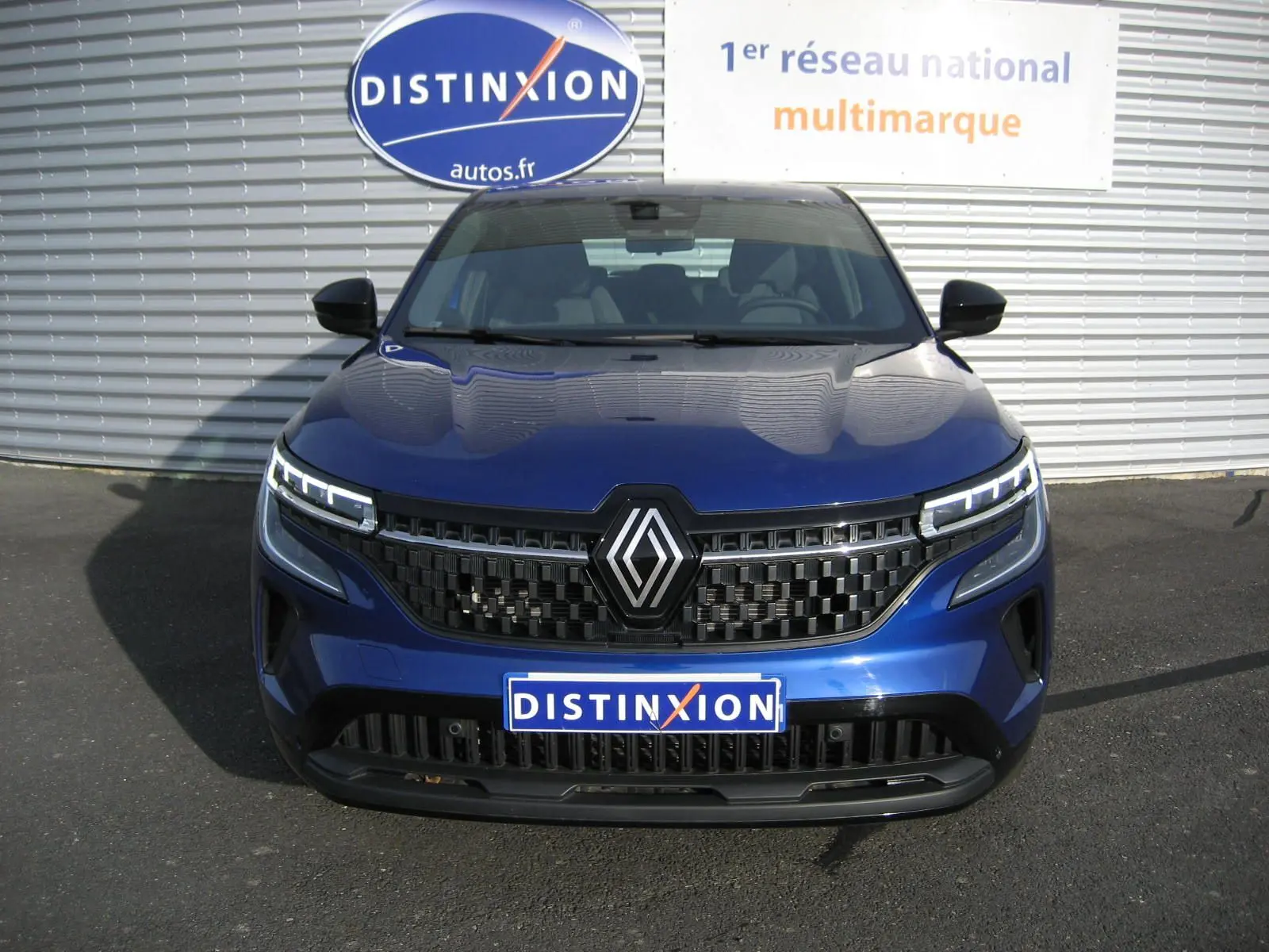 Vue frontale d’un Renault Austral bleu Iron 2025 avec calandre noire et feux LED distinctifs allumés.