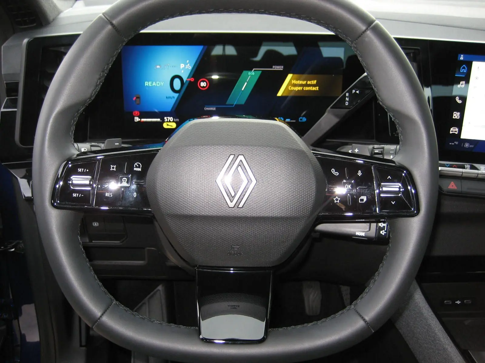 Vue rapprochée du volant multifonctions noir du Renault Austral 2025 avec tableau de bord numérique allumé.