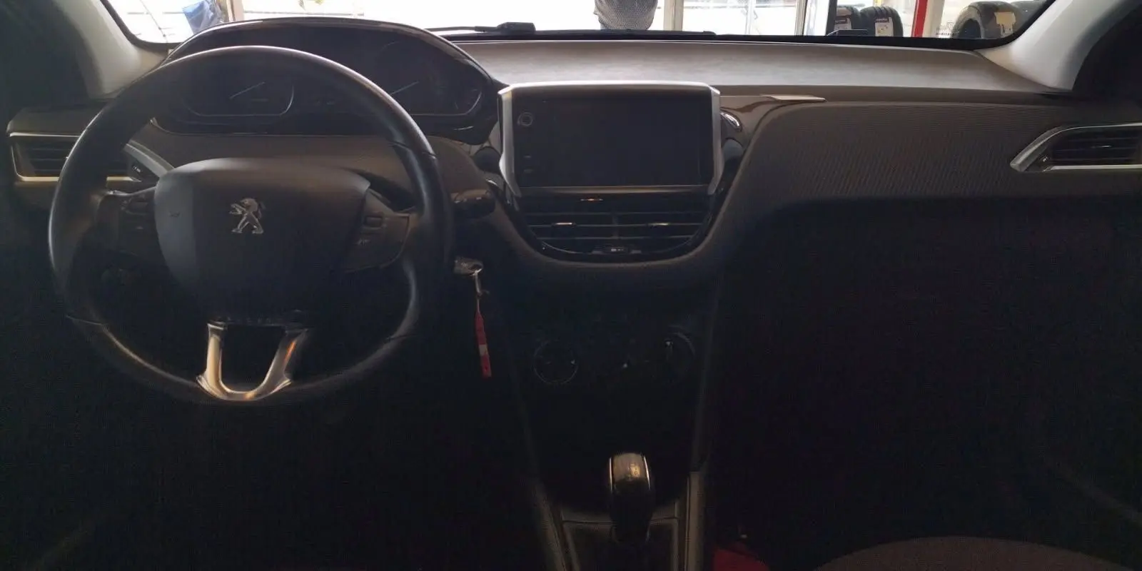 Vue intérieure du tableau de bord et volant noir d'une Peugeot 208 1.6l HDi 75 ch de 2023, avec écran central éteint.