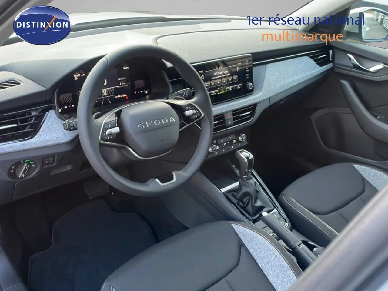 Vue intérieure avant droite du Skoda Kamiq gris argent, mettant en valeur le tableau de bord moderne et la console centrale.