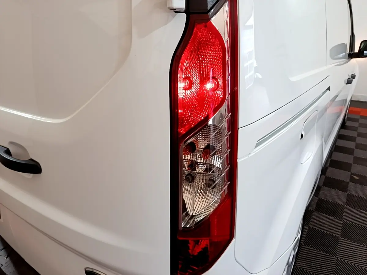 Gros plan sur le feu arrière droit d’un Ford Transit Fourgon blanc, avec vue partielle du flanc droit et de la porte arrière.