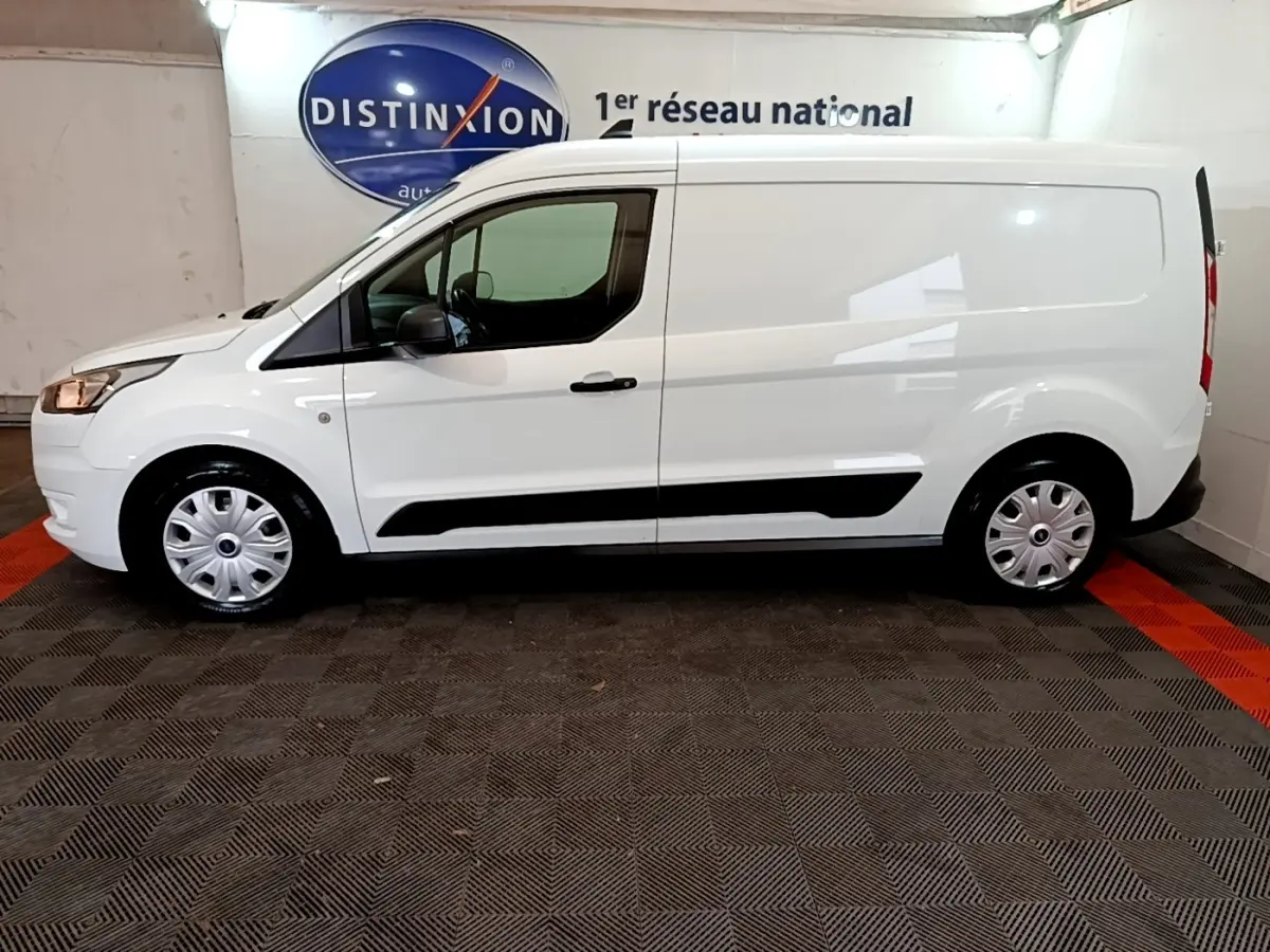 Vue de profil côté gauche d'un Ford Transit Fourgon blanc 2022 avec jantes acier et bandes noires latérales.