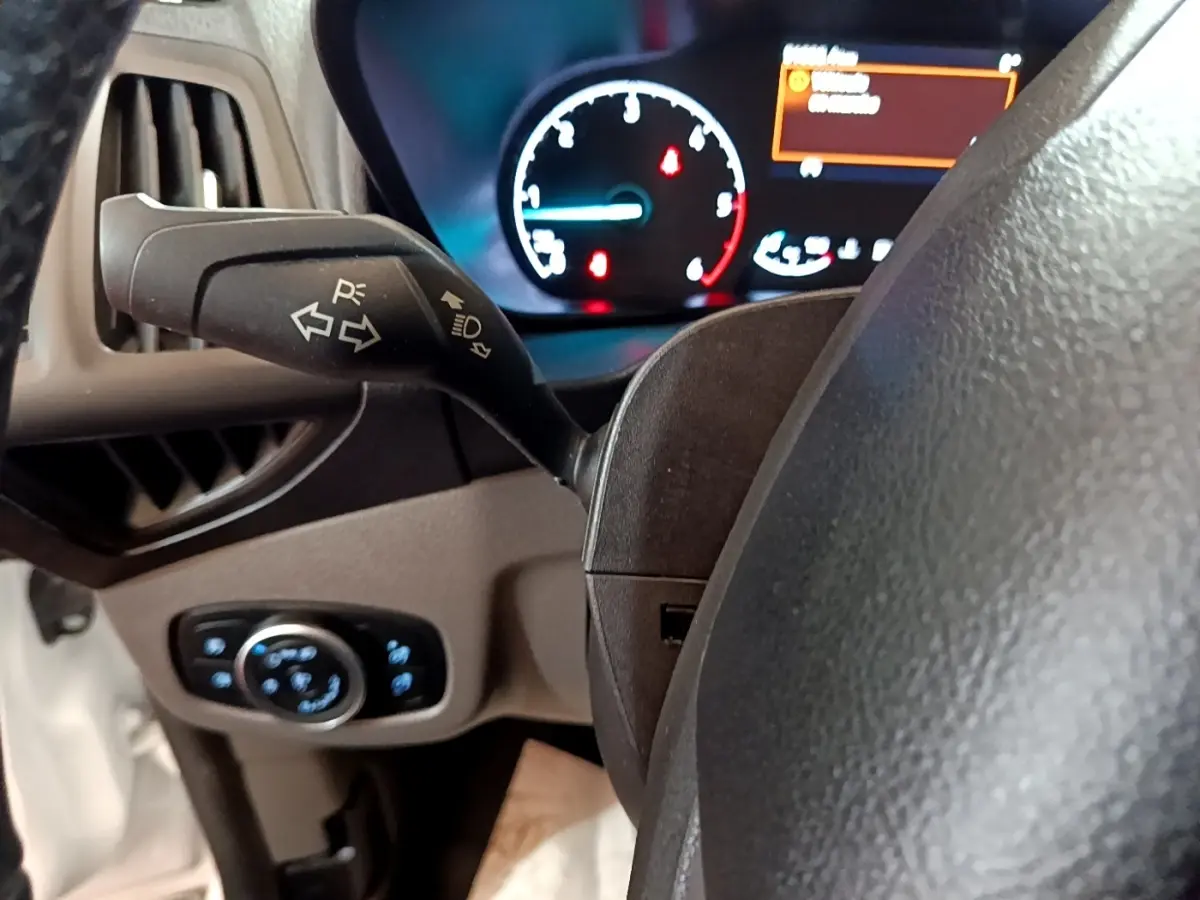 Gros plan sur le commodo gauche et le tableau de bord éclairé du Ford Transit Fourgon blanc, version 2022.