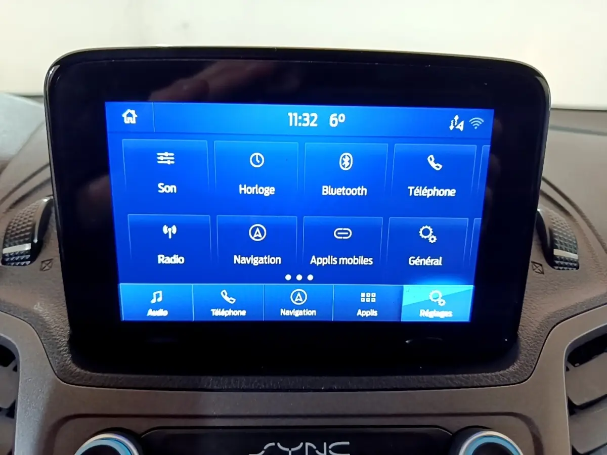 Écran tactile central bleu affichant les options multimédia du Ford Transit Fourgon blanc, vue intérieure frontale.