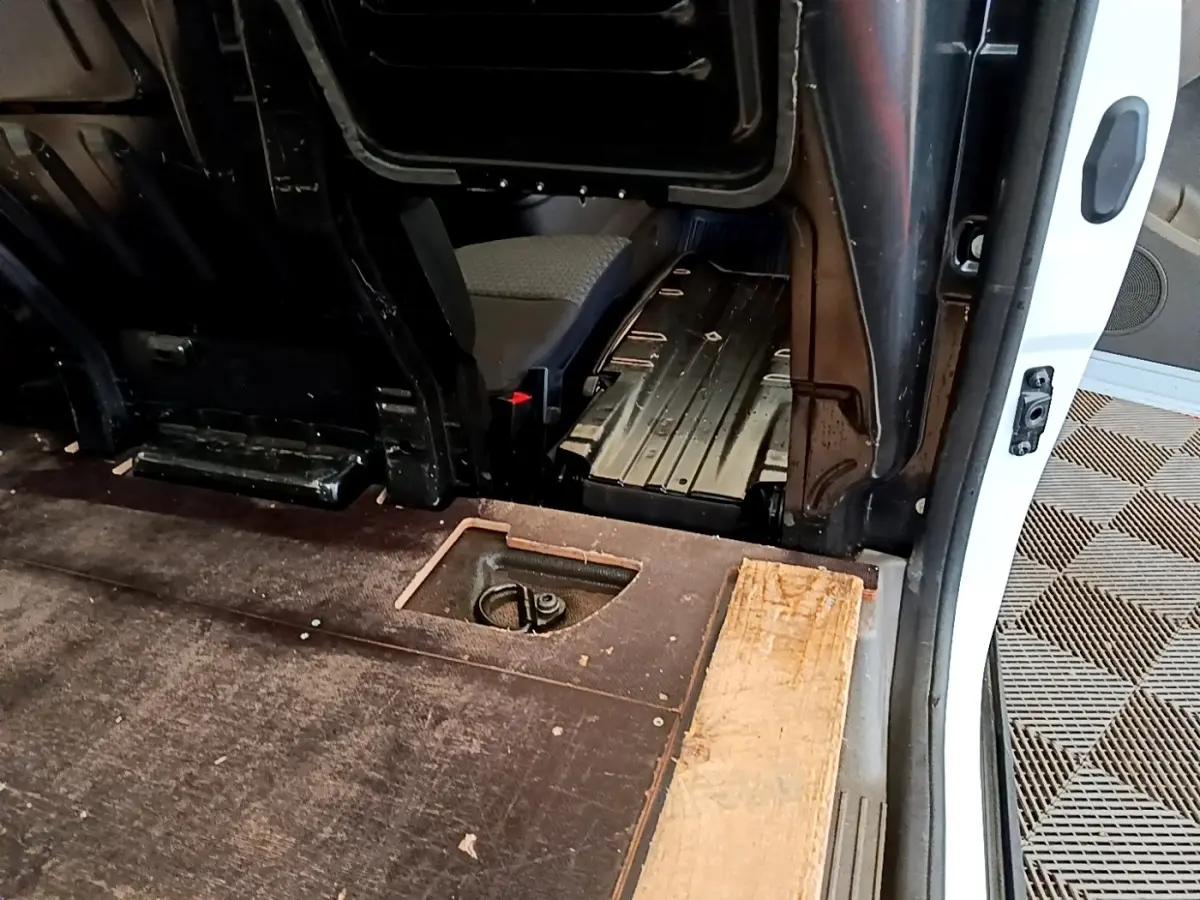 Vue intérieure côté droit du fourgon blanc Ford Transit, montrant l'espace de chargement et une cloison partielle.