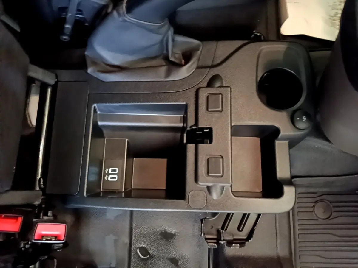 Vue plongeante sur la console centrale noire du Ford Transit Fourgon 2022, avec prise USB et porte-gobelet.