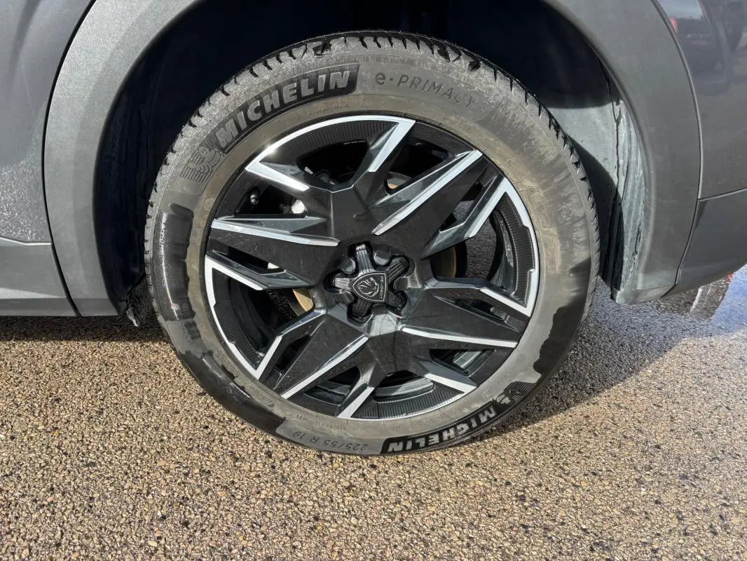 Gros plan sur la jante alliage 19 pouces noire et argentée du Peugeot 3008 Hybrid gris, avec pneu Michelin visible.