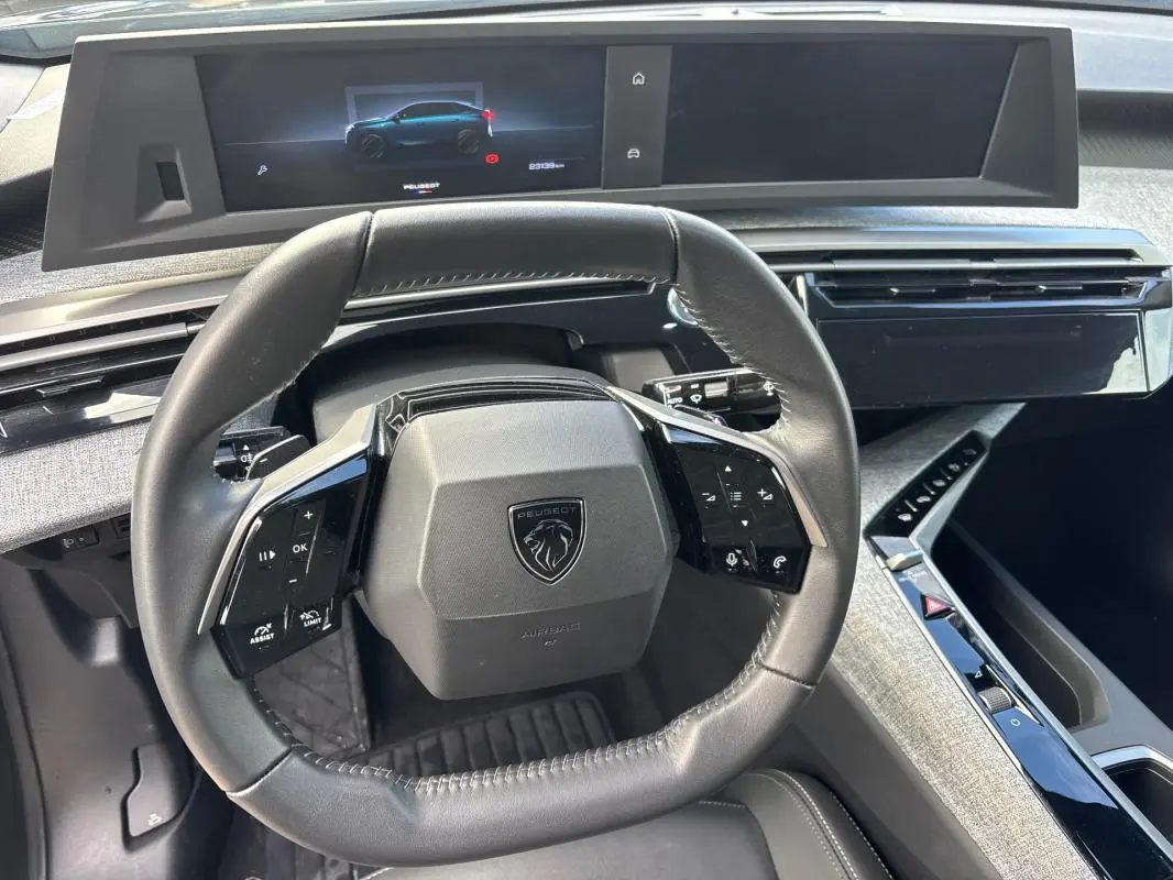 Vue intérieure centrée sur le volant cuir et le cockpit numérique du Peugeot 3008 Hybrid gris 2025.