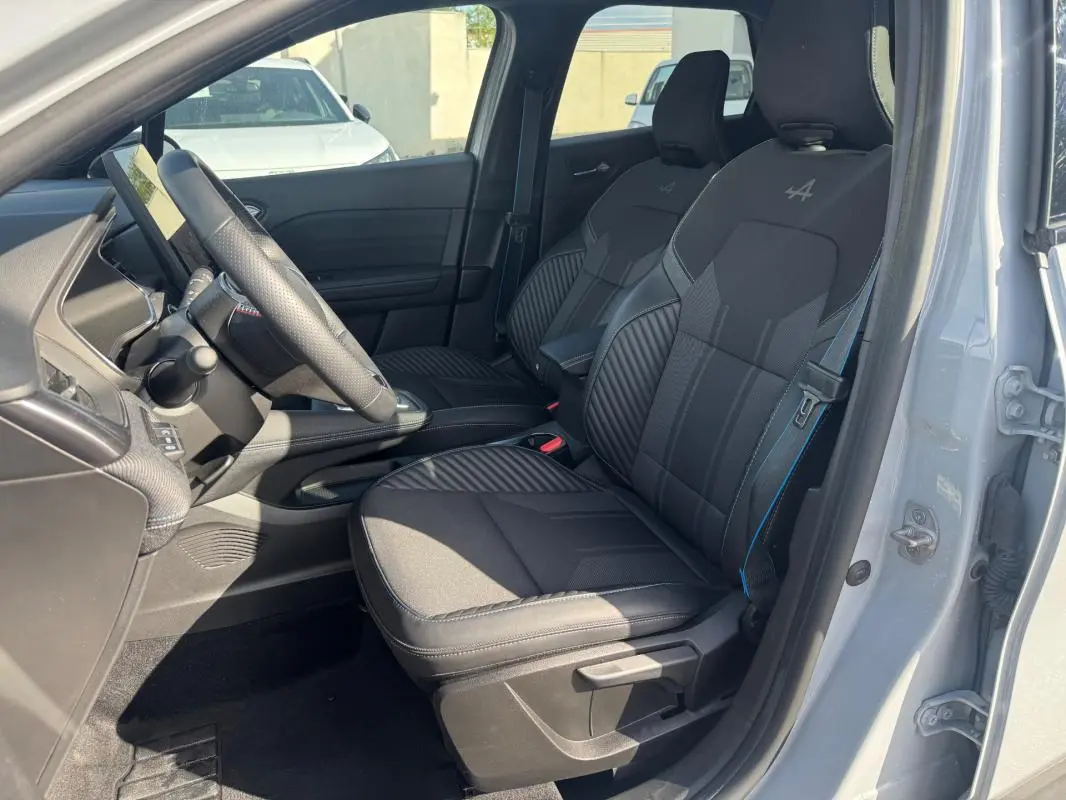 Intérieur avant droit d'une Renault Symbioz gris clair, sièges noirs avec logo Alpine brodé sur les appuie-têtes.