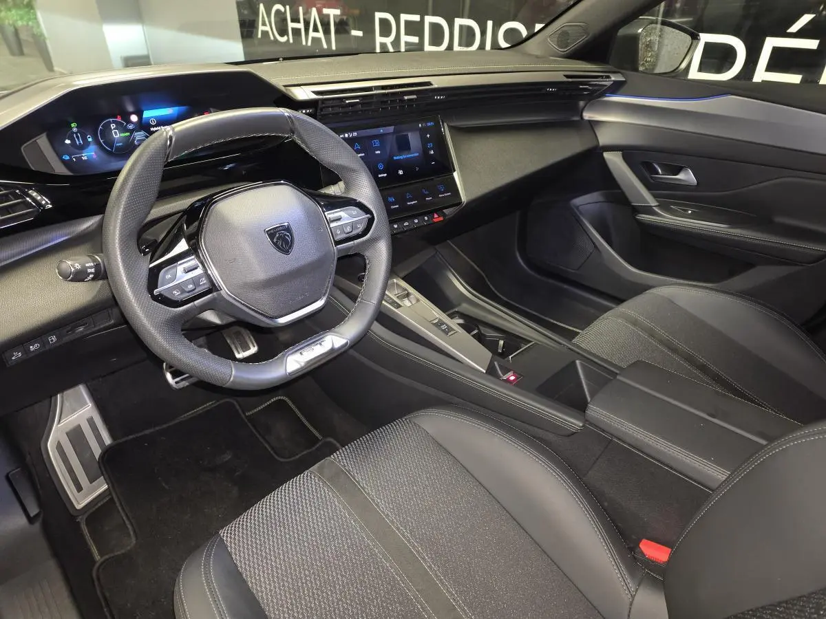 Vue intérieure côté conducteur de la Peugeot 408 gris, avec volant cuir perforé et écran tactile central.