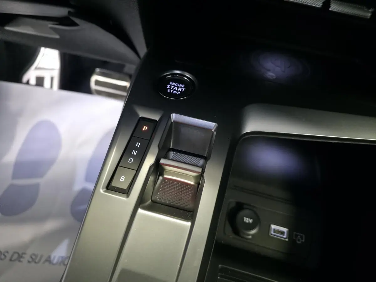 Gros plan sur la console centrale noire de la Peugeot 408 hybride, montrant la commande de boîte auto et bouton start/stop.