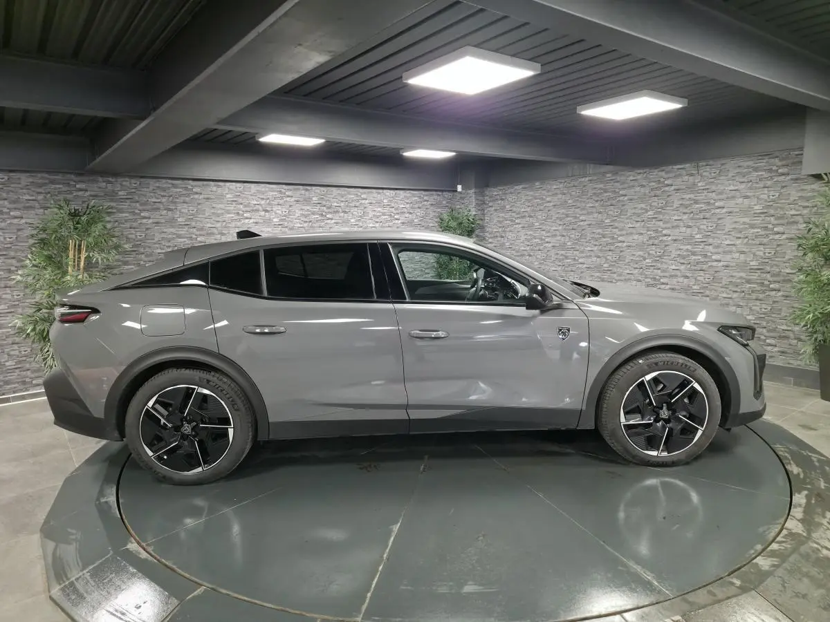 Peugeot 408 gris Selenium vue de profil côté gauche, jantes alliage 19 pouces et toit noir Mistral dans un showroom.