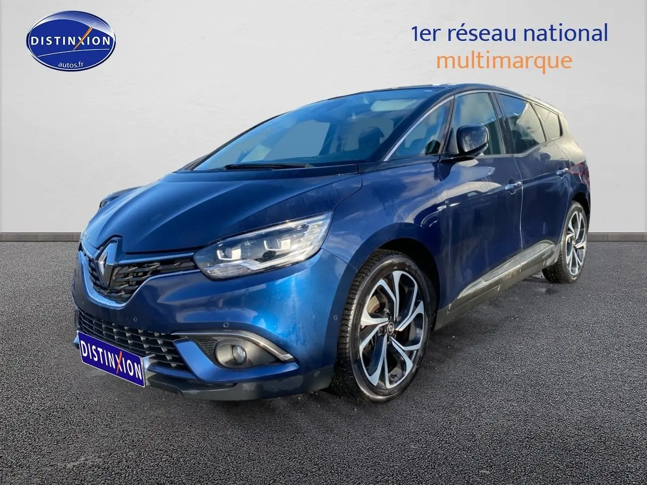 Renault Grand Scenic IV bleu en 3/4 avant droit, avec jantes alliage et feux LED allumés.