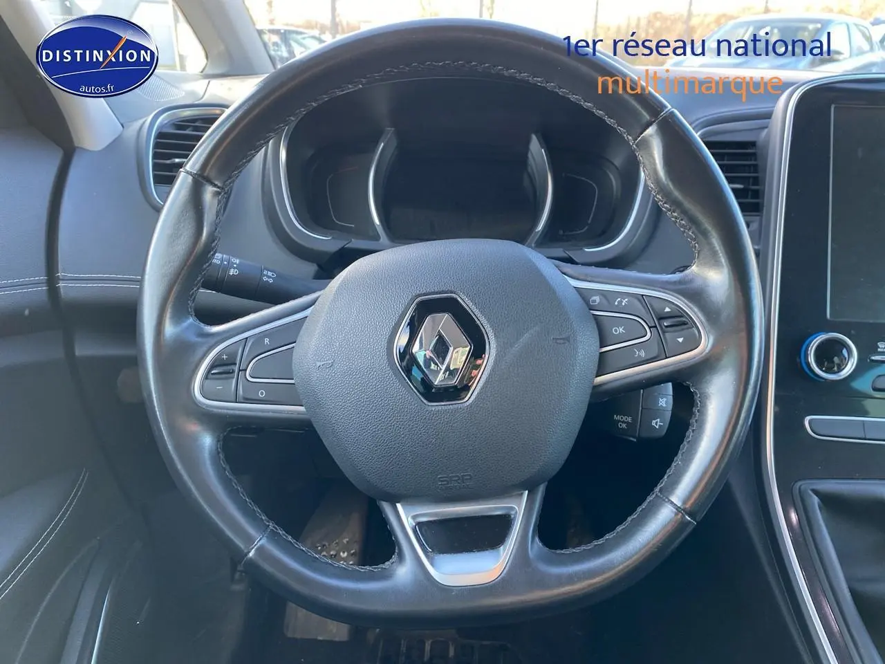 Volant cuir noir Renault Grand Scenic IV vu de face avec commandes intégrées et tableau de bord partiellement visible.