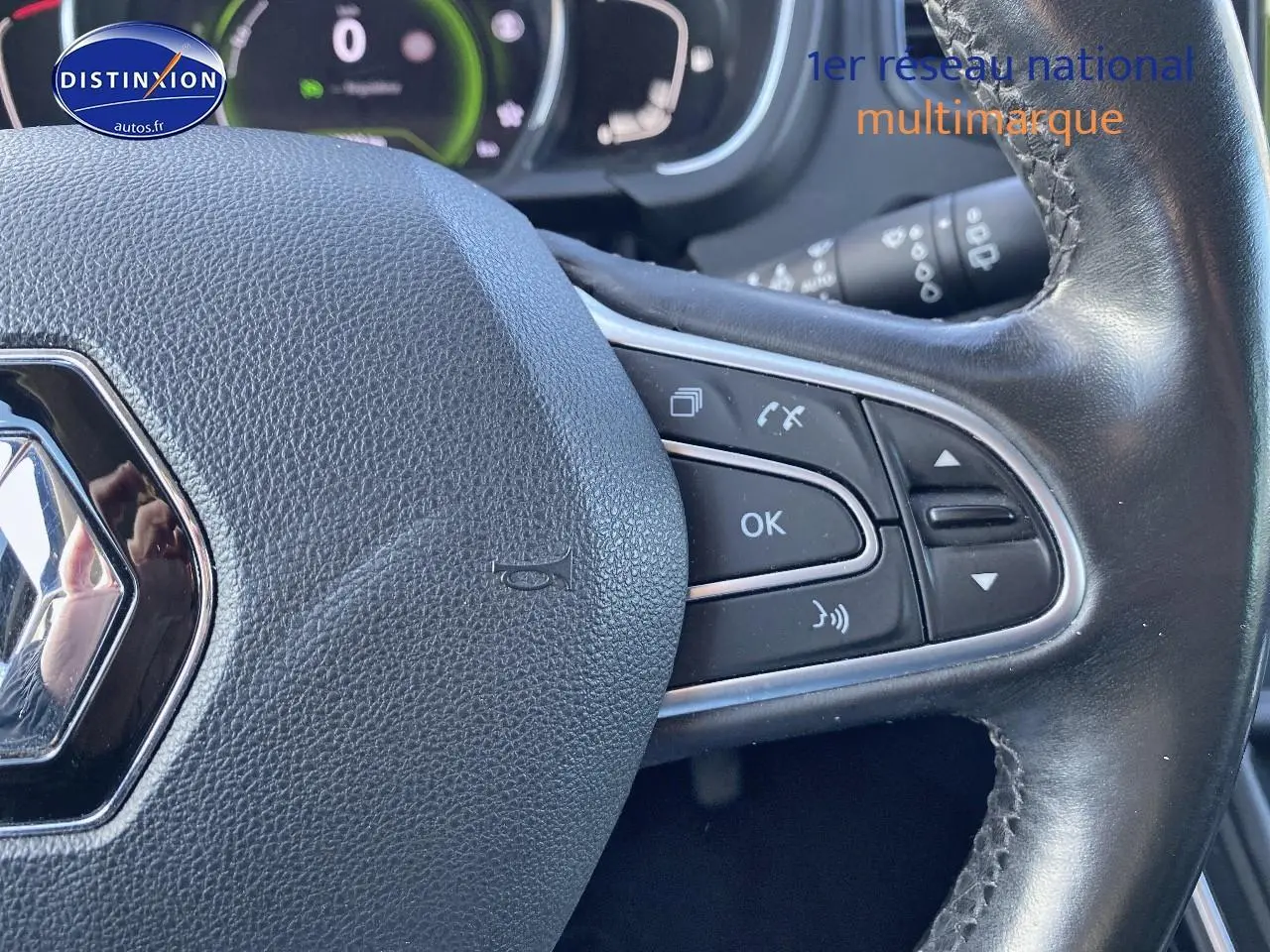 Gros plan sur le volant cuir noir du Renault Grand Scenic IV bleu, avec commandes multifonctions visibles à droite.