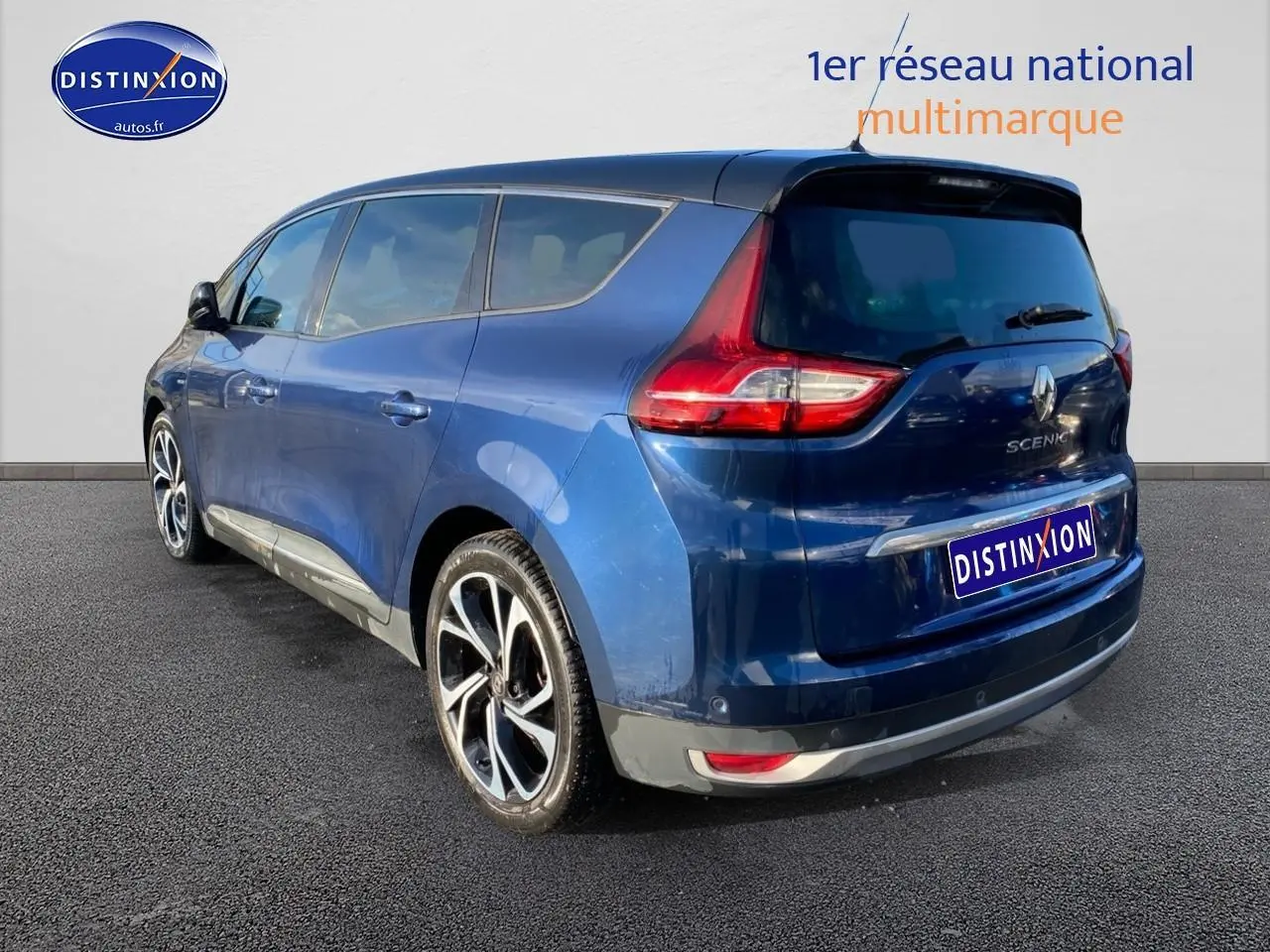 Vue 3/4 arrière droite d'un Renault Grand Scénic IV bleu avec jantes alliage 20 pouces et vitres surteintées.