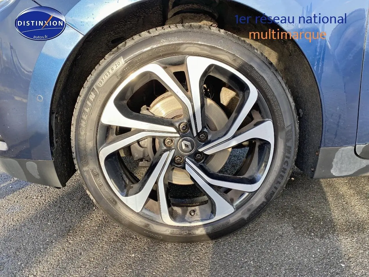 Gros plan sur la roue avant gauche du Renault Grand Scenic IV bleu, avec jante alliage 20 pouces et logo Renault central.