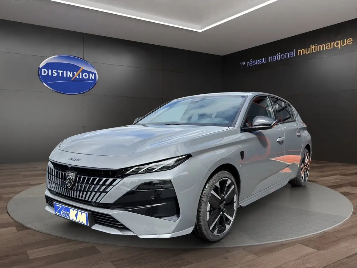 Peugeot 308 gris clair en vue 3/4 avant droit, avec calandre distinctive et jantes noires bicolores.