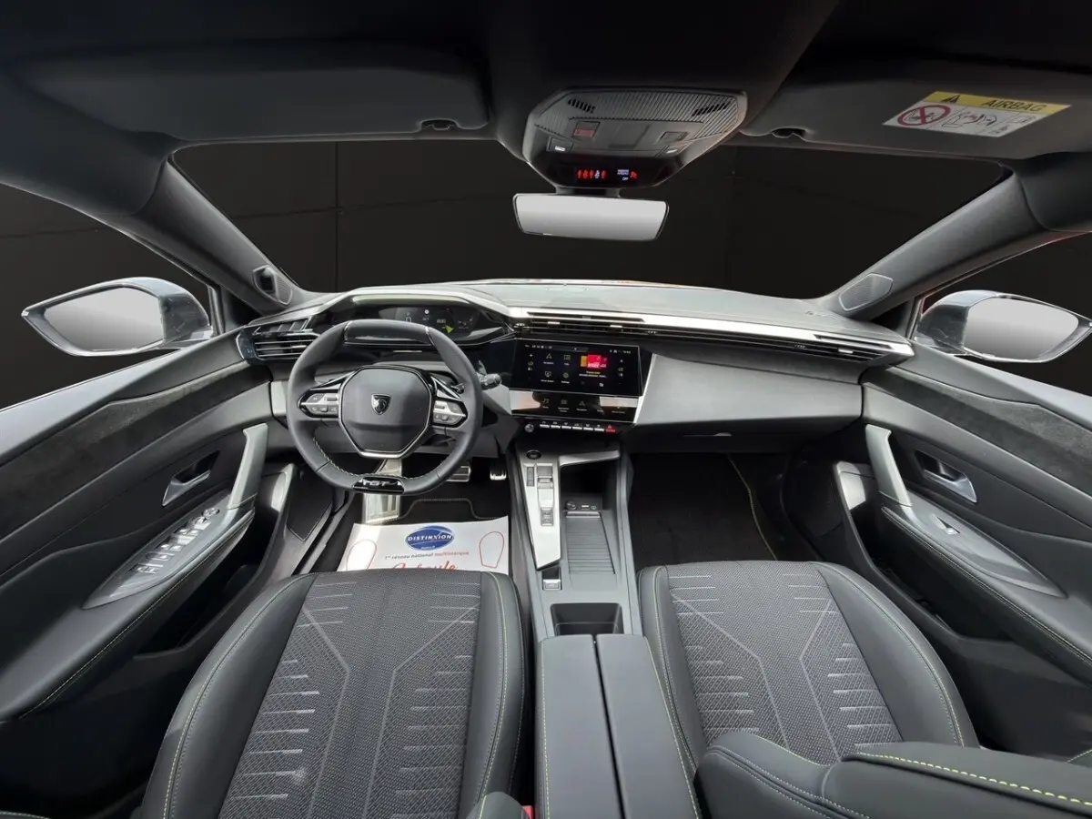 Vue intérieure avant de la Peugeot 308 2026, sièges noirs et tableau de bord moderne avec écran tactile central.