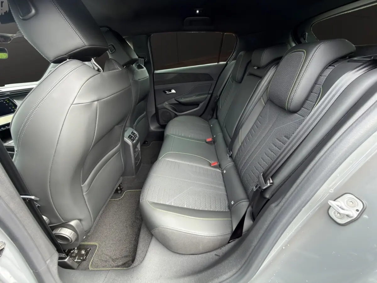 Vue intérieure arrière côté droit de la Peugeot 308 gris clair, sièges en cuir et tissu avec surpiqûres vertes.