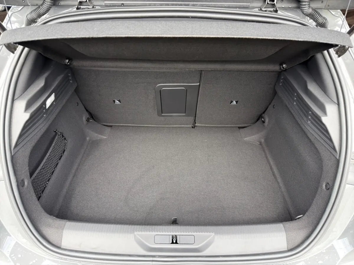 Coffre ouvert vu de dessus de la Peugeot 308 gris clair, espace de rangement spacieux et tapis noir.