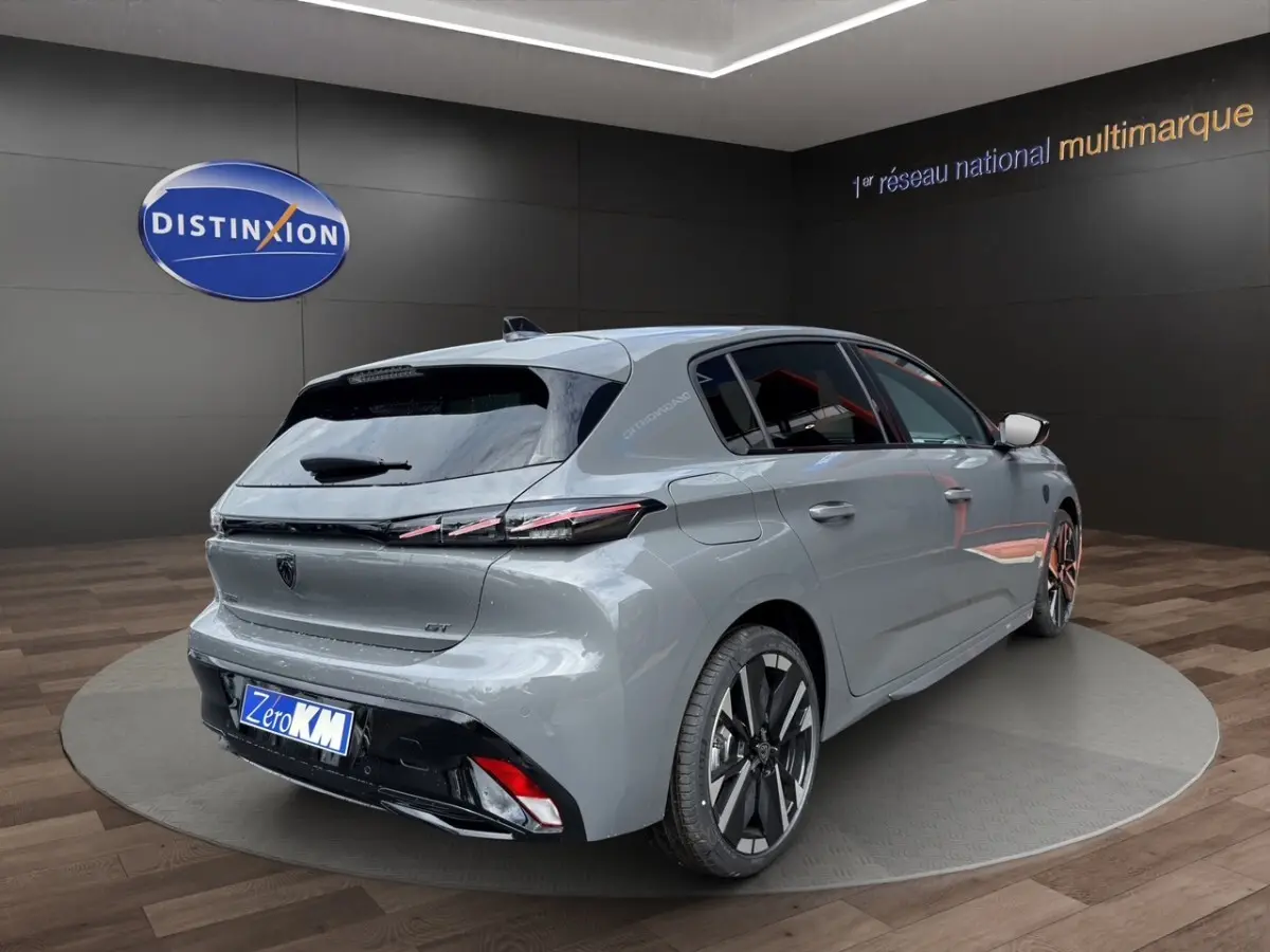 Vue 3/4 arrière droite d'une Peugeot 308 GT gris clair avec feux LED et jantes alliage bicolores.