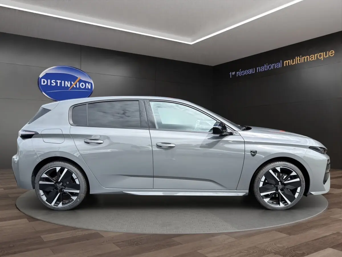 Profil côté droit de la Peugeot 308 GT gris clair 2026 avec jantes noires et détails sportifs visibles.
