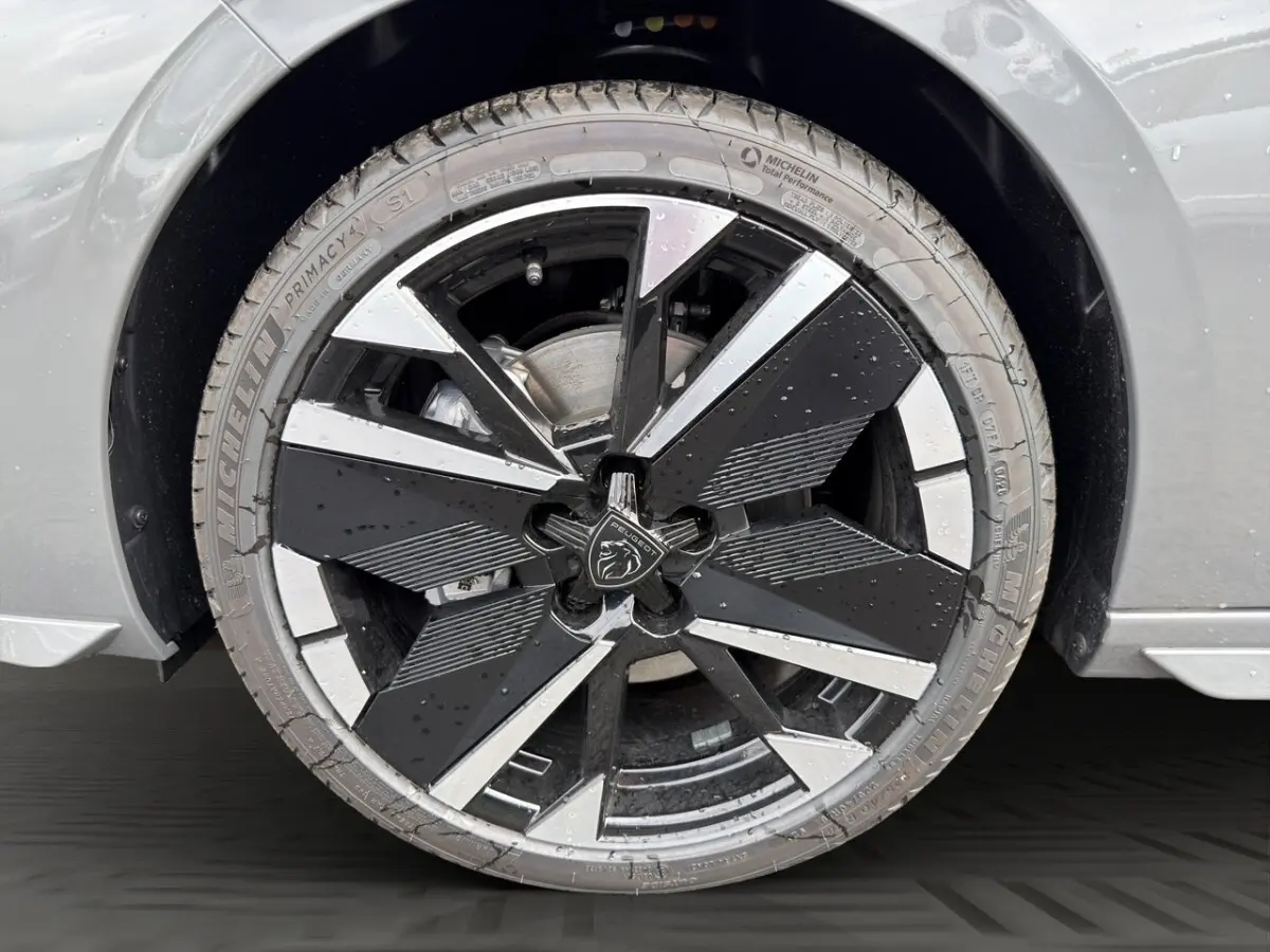 Gros plan sur la roue avant droite gris clair de la Peugeot 308 avec jante noire et argentée au design géométrique.