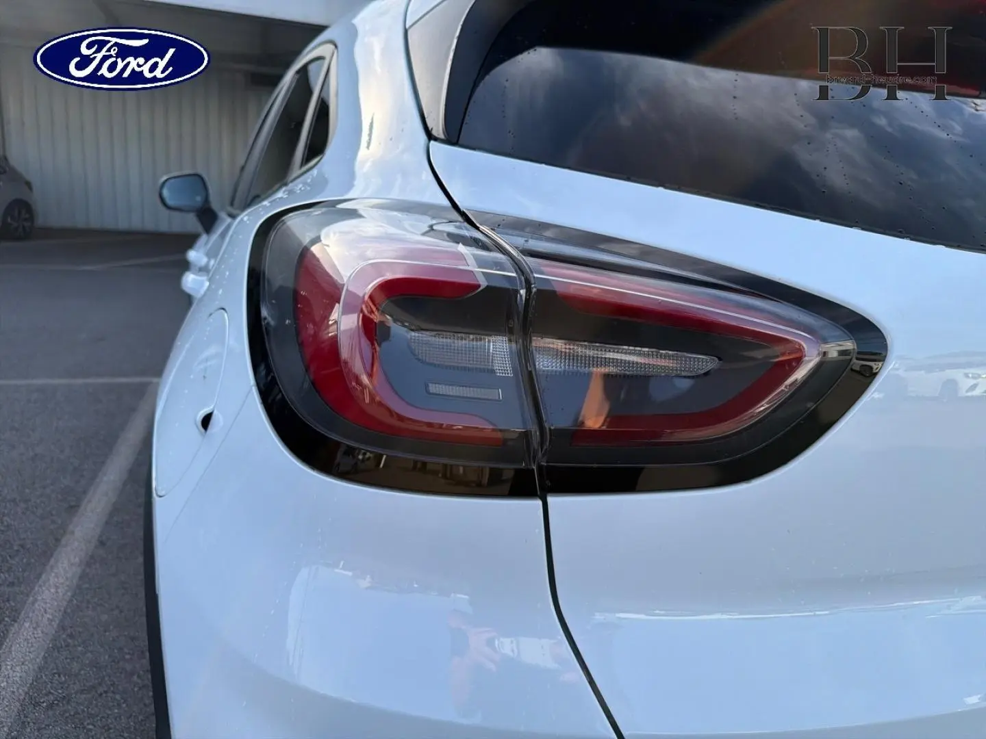 Gros plan sur le feu arrière gauche d’un Ford Puma blanc Glacier, avec hayon électrique visible en partie.
