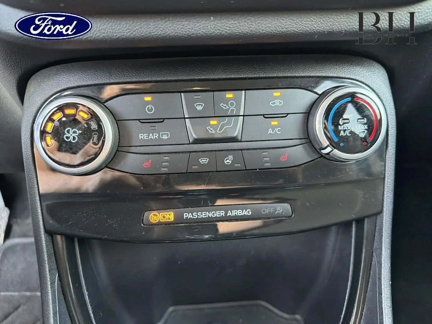 Vue rapprochée du tableau de bord central noir du Ford Puma 2023, montrant les commandes de climatisation et l'indicateur airbag passager.
