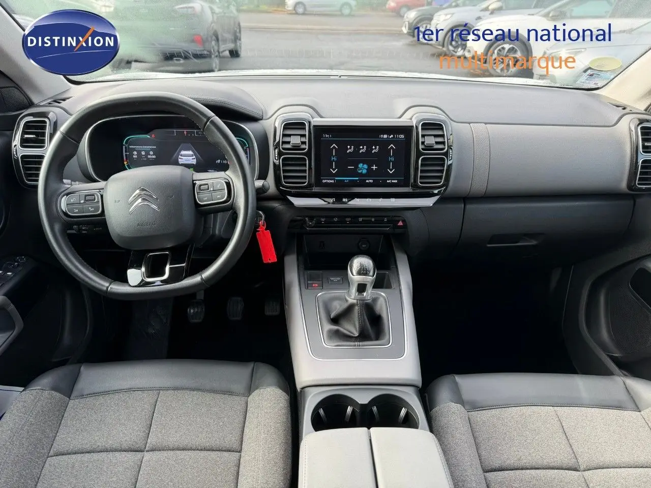 Vue intérieure avant du Citroën C5 Aircross blanc nacré, montrant tableau de bord, volant et console centrale avec boîte manuelle.