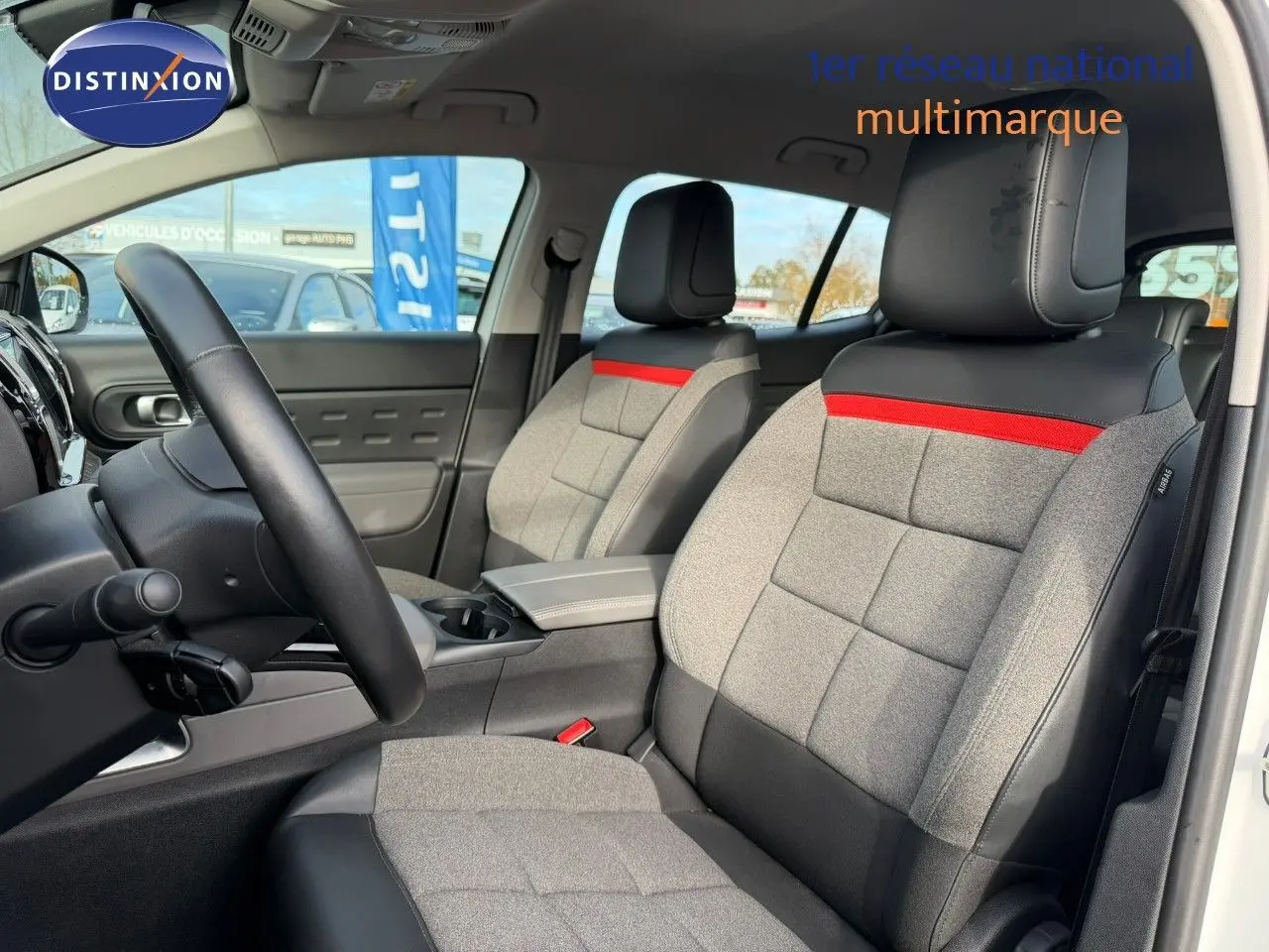 Vue intérieure des sièges avant en tissu gris et cuir noir avec bande rouge, dans un Citroën C5 Aircross blanc nacré.
