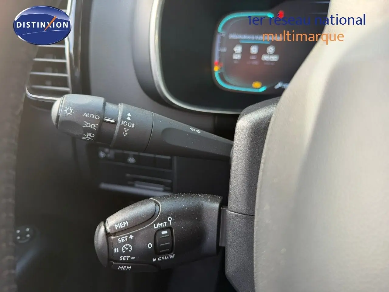 Gros plan sur les commandes au volant du Citroën C5 Aircross blanc nacré, avec tableau de bord numérique en arrière-plan flou.