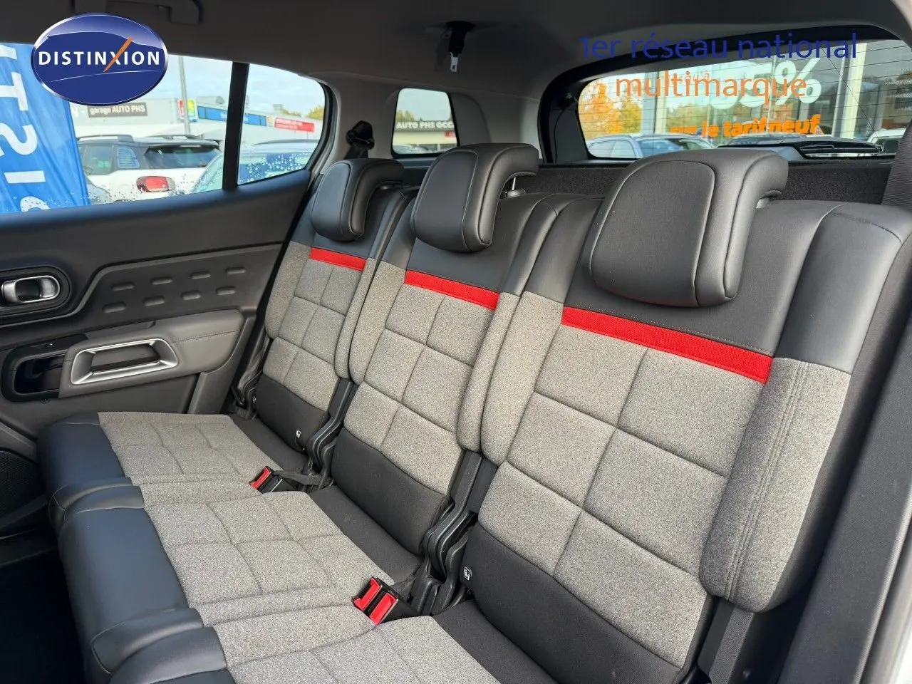 Vue intérieure des sièges arrière du Citroën C5 Aircross blanc nacré, avec sellerie grise, noire et bande rouge distinctive.