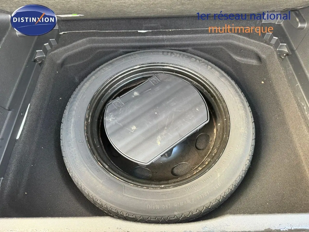 Vue rapprochée de la roue de secours noire dans le coffre d’un Citroën C5 Aircross blanc nacré de 2019.