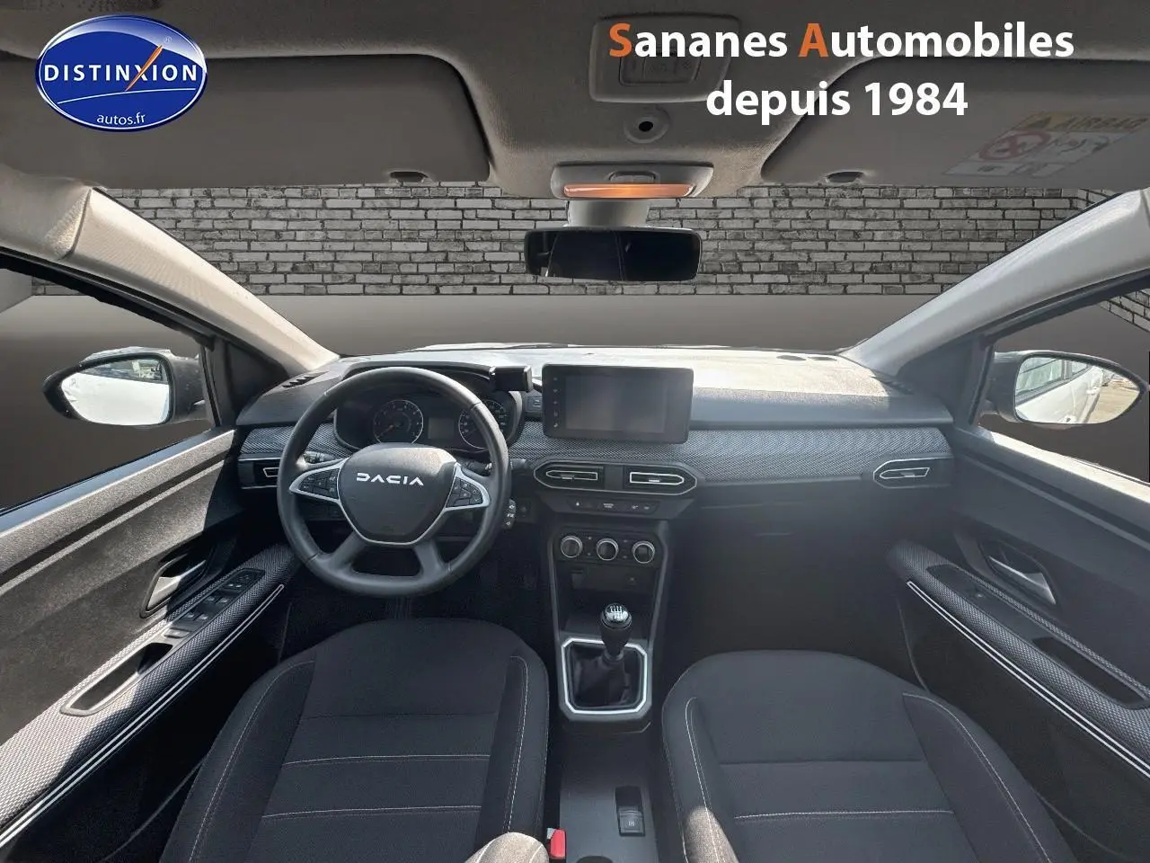 Vue intérieure avant du Dacia Jogger blanc, volant multifonction, écran tactile et levier de vitesses manuel visibles.