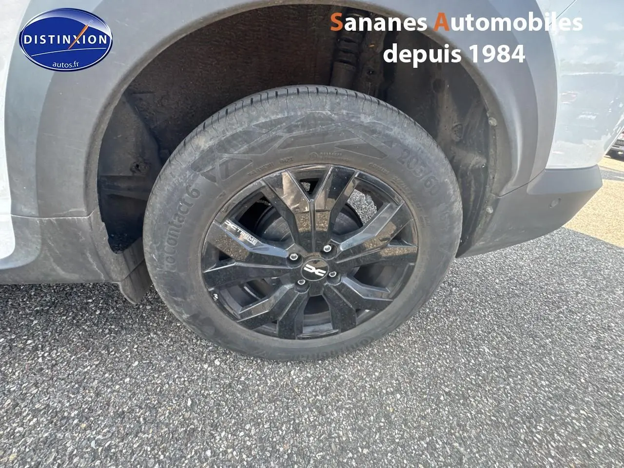 Gros plan sur la roue arrière gauche avec jante aluminium noire du Dacia Jogger blanc Glacier 2023 version Extrême+