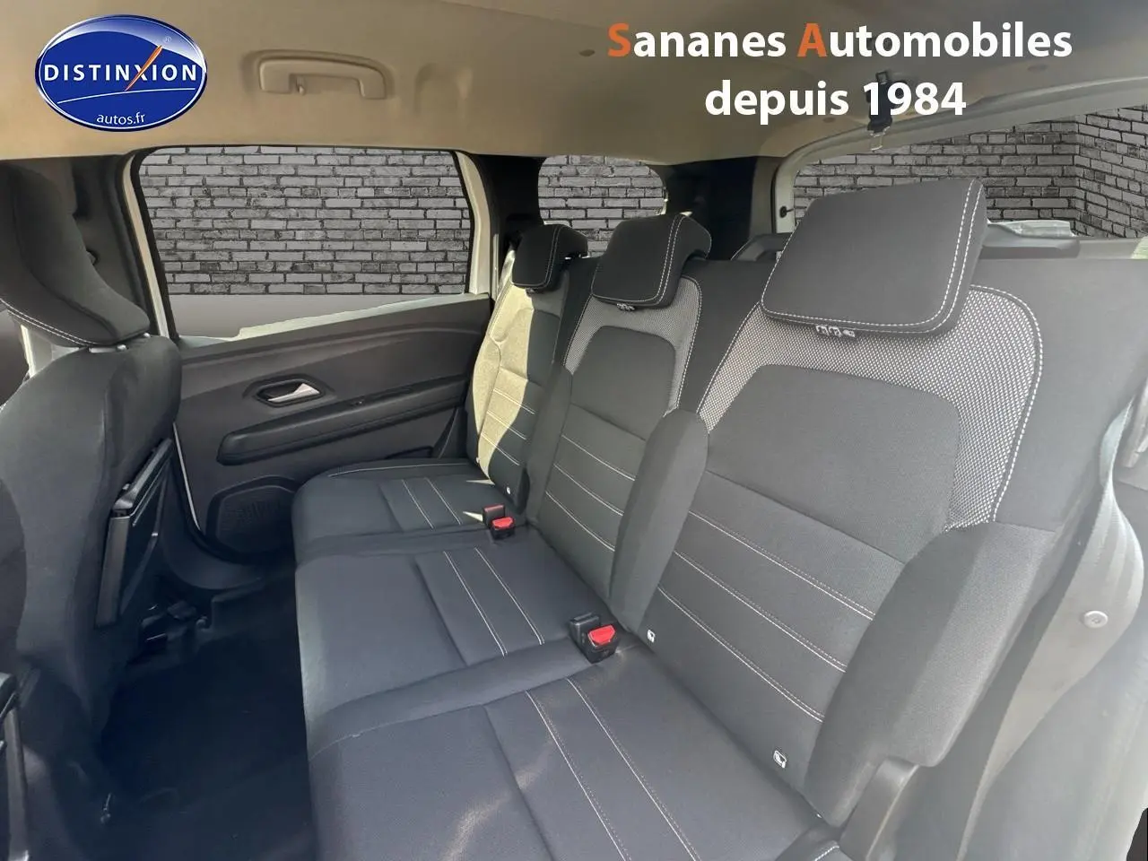 Vue intérieure du siège arrière droit du Dacia Jogger blanc, montrant la banquette trois places en tissu noir avec surpiqûres blanches.