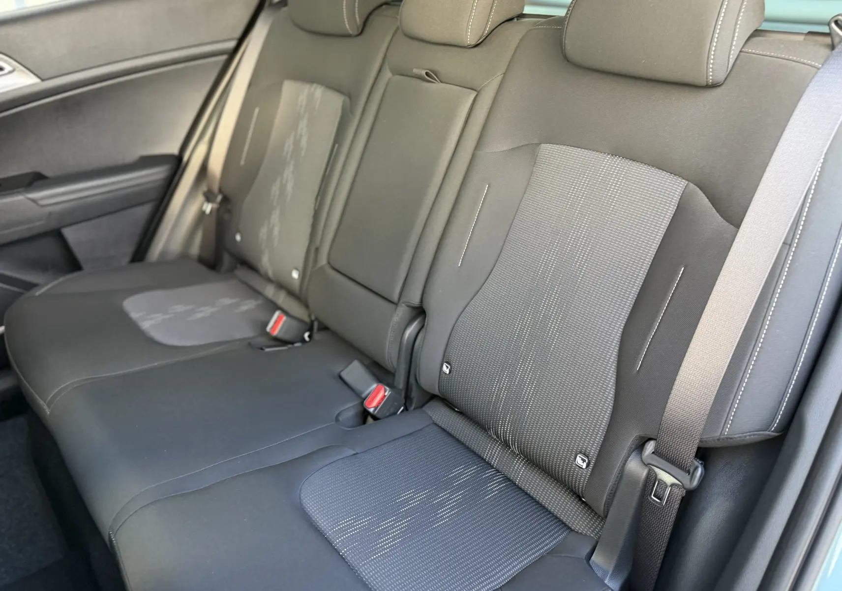 Vue intérieure centrée sur le volant noir et le tableau de bord numérique du Kia Sportage 2025 gris Sirius.